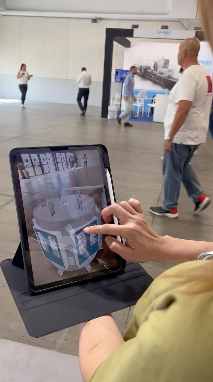 Visitor viewing an augmented-reality Yuexi machine model on a tablet at Marmomac